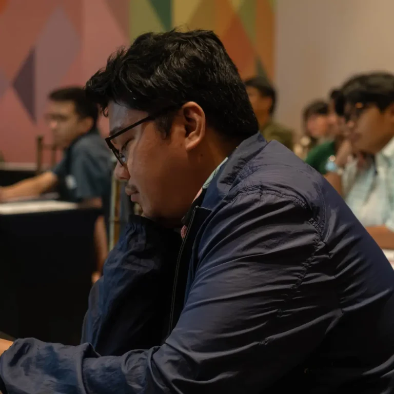 Man wearing glasses seated at a table during a community panel event