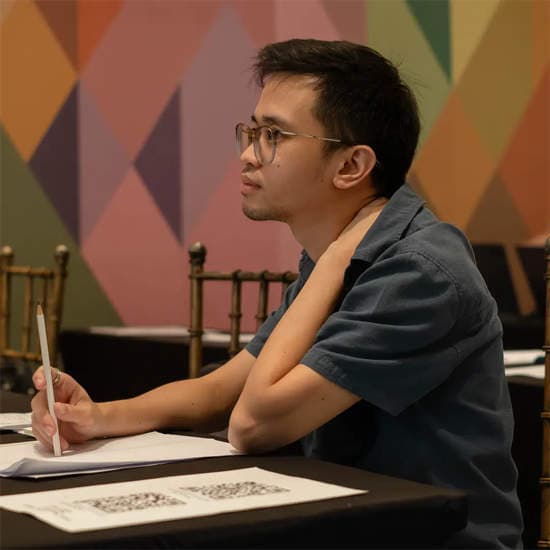 A man with glasses sitting at a corporate table, listening thoughtfully during a partnership event.